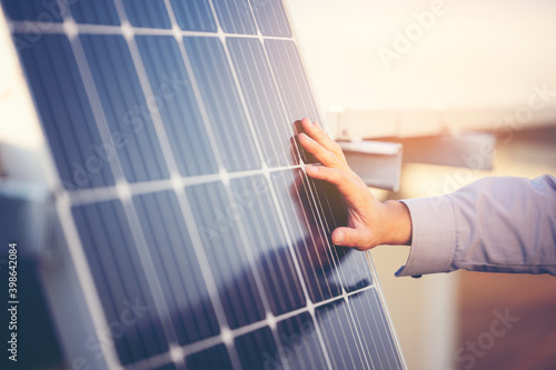 Close up of engineer hand is checking an operation of sun and cleanliness of photovoltaic solar panels on a sunset. Concept: renewable energy, technology,electricity,service, green,future photo