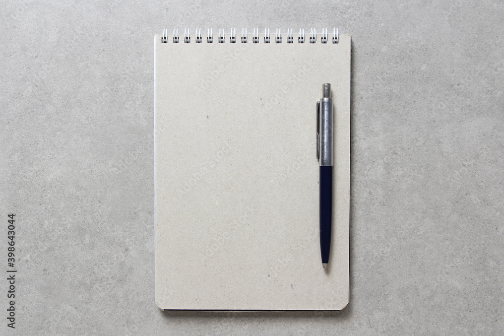 A spring notebook with a sheet of craft paper A5 with a ballpoint pen on light grey concrete background. Concept of new idea, business plan and strategy. Empty space for text A spring notebook with a sheet of craft paper A5 with a ballpoint pen on light grey concrete background. Concept of new idea, business plan and strategy. Empty space for text