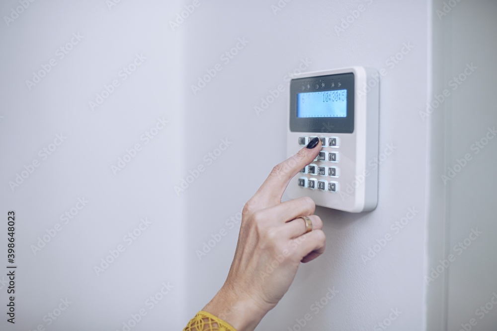 Security home system. Woman entering secret code on home alarm