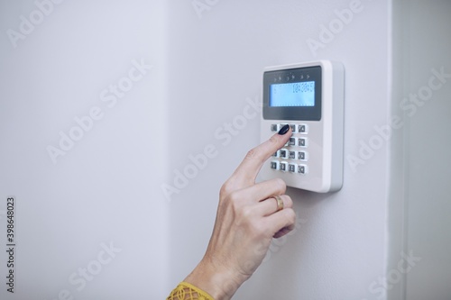Security home system. Woman entering secret code on home alarm