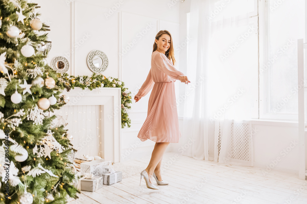 Beautiful cheerful happy young girl with christmas gifts on the background of a new year tree at home Beautiful cheerful happy young girl with christmas gifts on the background of a new year tree at home
