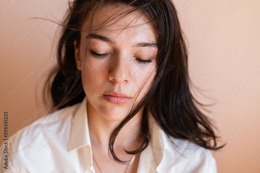 Beautiful young woman posing on beige wall background.