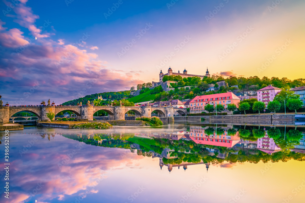 Marienberg Fortress and the Old Main Bridge reflecting in river on colorful sunset. Wurzburg, Bavaria, Germany