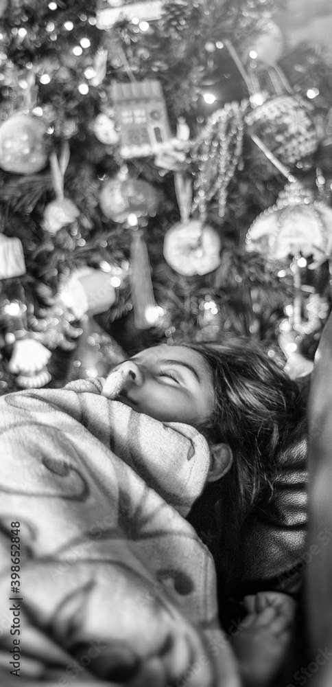 Young girl sleeping on the sofa with Christmas Tree in the background
