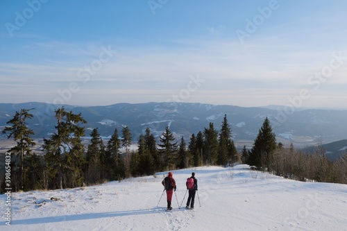 Winter mountain views on red ridge trail from Certovica - Sedlo za Lenivou - Sedlo Homolka during snowshoe tours in Low Tatras in Slovakia. Silhouettes of standing tourists on snowshoes.