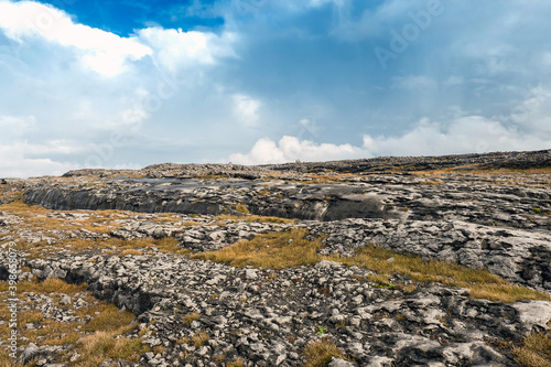 Epic landscape in Burren area, West of Ireland. Rough stone terrain. Warm sunny day, Cloudy sky. Nobody. Travel and explore nature concept