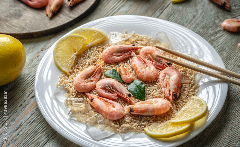 Appetizing delicious frozen dish of shrimps and rice with lemon on a wooden table. Concept of ready made frozen food for dinner like in a restaurant at home Appetizing delicious frozen dish of shrimps and rice with lemon on a wooden table. Concept of ready made frozen food for dinner like in a restaurant at home