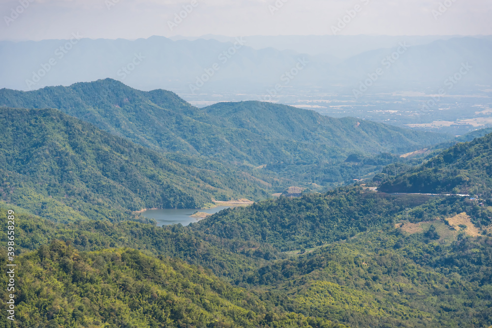 Mountain view morning on top hills and green forest cover with soft mist and blue sky background.Thailand.