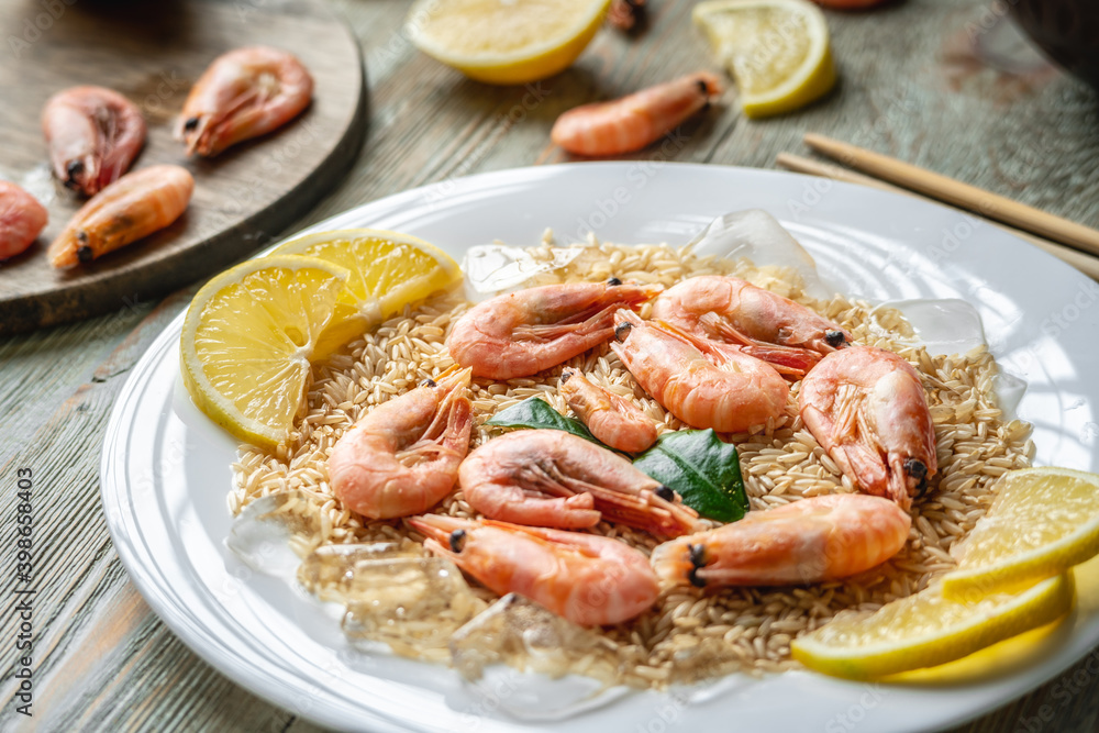 Appetizing delicious frozen dish of shrimps and rice with lemon on a wooden table. Concept of ready made frozen food for dinner like in a restaurant at home Appetizing delicious frozen dish of shrimps and rice with lemon on a wooden table. Concept of ready made frozen food for dinner like in a restaurant at home
