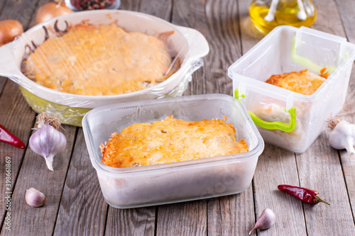 Casserole in containers and in a baking dish on a wooden table.