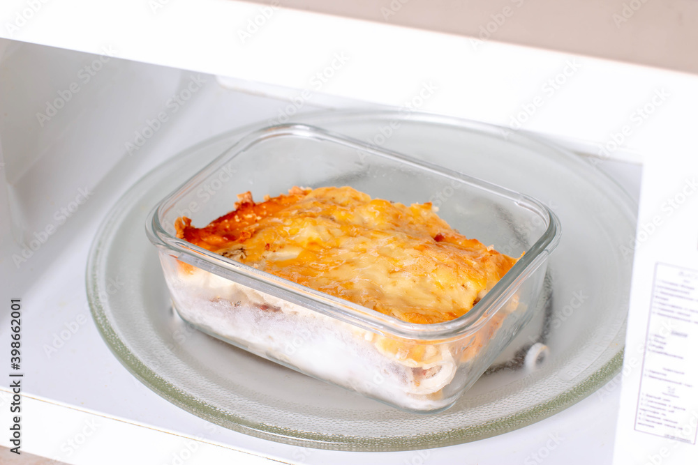 Potato casserole with meat in a container in the microwave. Ready meals Potato casserole with meat in a container in the microwave. Ready meals