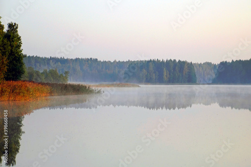 Fototapeta Naklejka Na Ścianę i Meble -  Early morning on a forest lake in September. Light fog and reflection in the water.