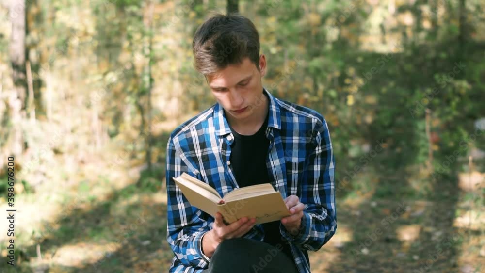 Guy reads a book while sitting in the park Guy reads a book while sitting in the park