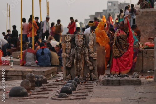Bokeh shot of an open temple of lord Shiva at the ghats of Varanasi with selective focus. Ancient statue of indian god with six hands. People praying on 22 November, 2020, Varanasi, India.