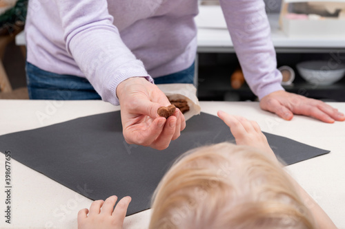 Woman gives candy to child. Kid reaches for the candy. Close up