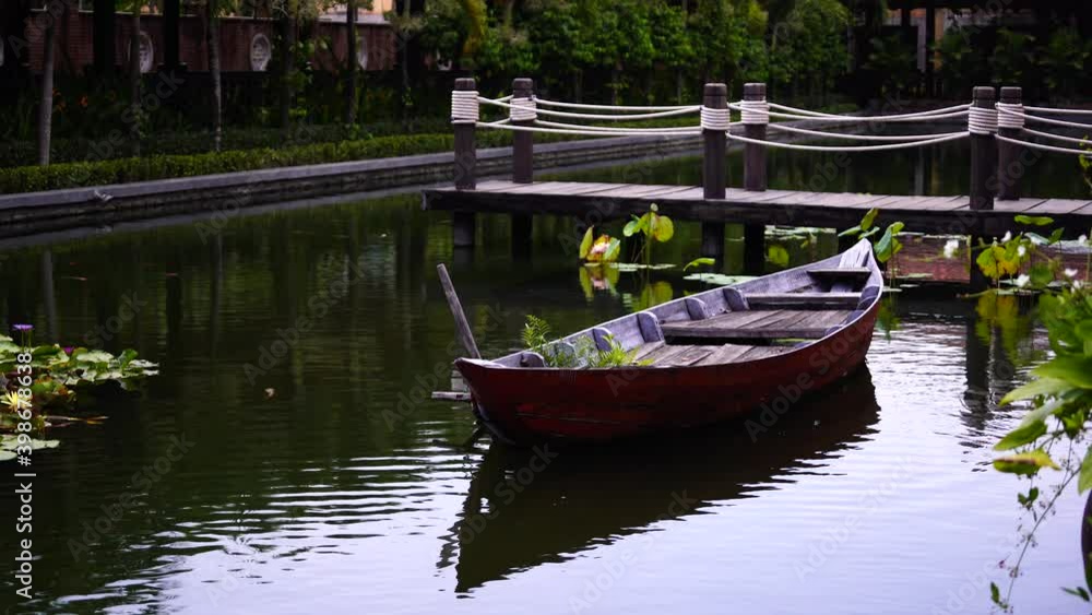 Wooden boat on the pond near the pier in a tropical garden in Danang, Vietnam. Travel and nature concept Wooden boat on the pond near the pier in a tropical garden in Danang, Vietnam. Travel and nature concept