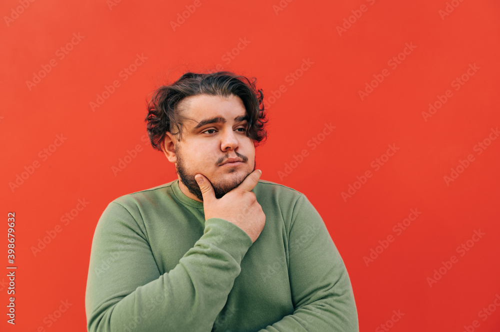 Closeup portrait of a thoughtful handsome bearded hispanic guy, touching his chin with his hand, expressing a thinking gesture, pondering over something, looking aside. Closeup portrait of a thoughtful handsome bearded hispanic guy, touching his chin with his hand, expressing a thinking gesture, pondering over something, looking aside.
