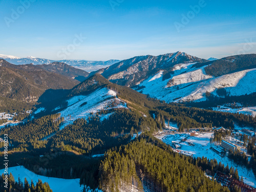 Winter Mountain Peaks and a Valley at a Ski Resort on a Sunny Day. Aerial View