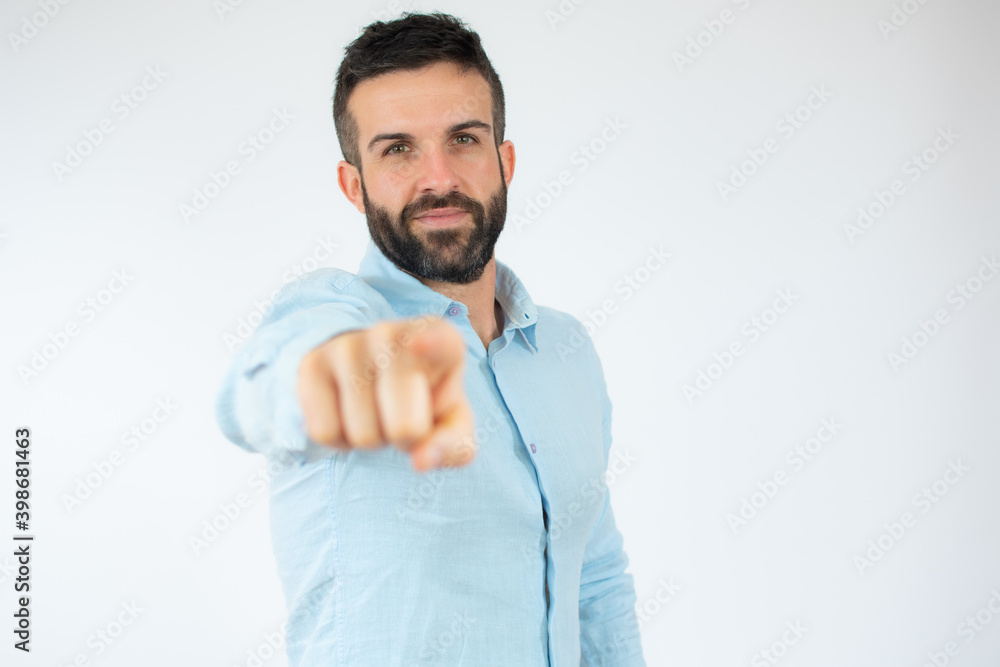 Young man wearing casual blue shirt pointing finger to camera over white background. Young man wearing casual blue shirt pointing finger to camera over white background.
