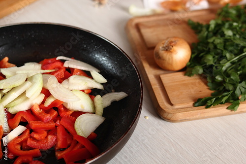 Frying pan with sliced onion and red bell pepper. Making Chicken and Egg Galette Series.