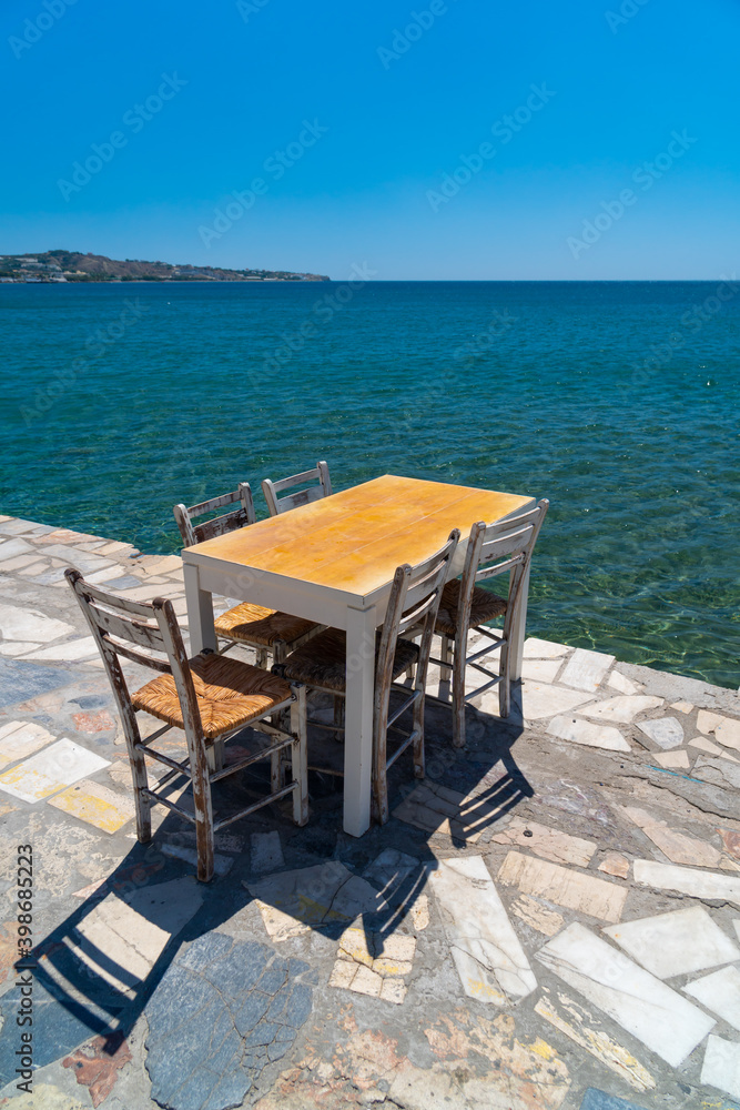 Magnificent panoramic view on a coast beauty. Peaceful place. Served tables. Table and chairs at a traditional greek restaurant by the beach. Lerapetra, Crete.