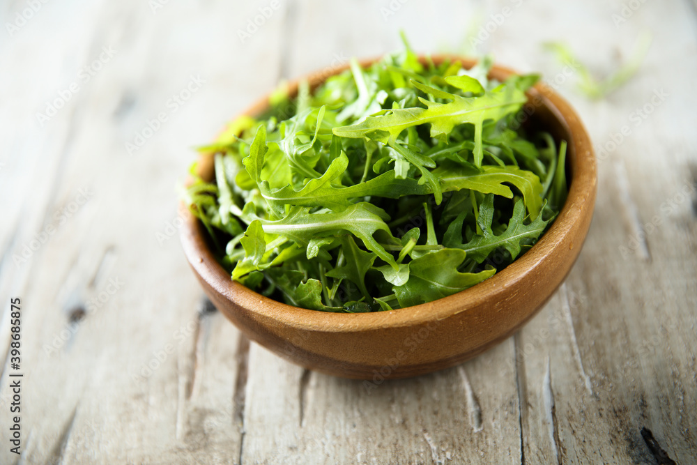 Healthy fresh arugula in a wooden bowl Healthy fresh arugula in a wooden bowl