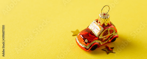 Christmas greeting card concept with red car toy over yellow. Festive banner with copy space