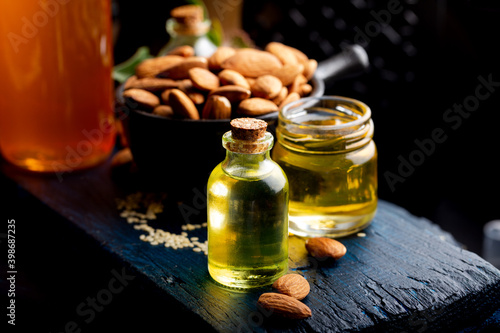 Concept of organic vegetable oils for cooking and cosmetology. Almond essential oil on a dark wooden background