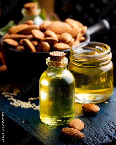 Concept of organic vegetable oils for cooking and cosmetology. Almond essential oil on a dark wooden background