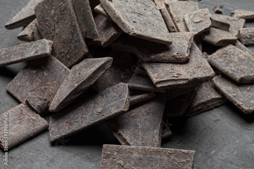 Fototapeta Naklejka Na Ścianę i Meble -  Raw 100% pure organic cocoa chocolate bar isolated on black stone background with shadow. Theobroma cocoa mass or paste