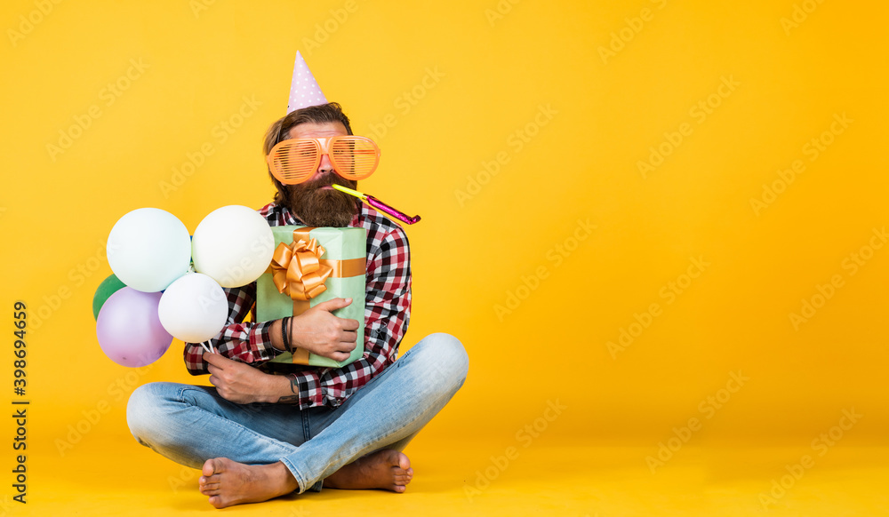 anniversary. have a happy holiday. party time. happy birthday to you. bearded mature man celebrate birthday party. copy space. man in bday hat hold holiday balloons. gifts and presents concept