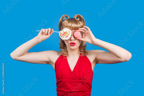Pin Up girl with lollipop on stick isolated on blue background. Sweetness. Smiling woman with colorful lollipop. Junk food, sweet food, diet, dieting concept.