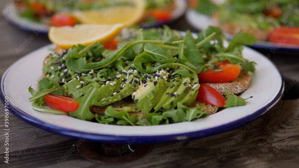 Healthy food trends in vegan restaurant menu. Three servings of avocado toast with salad and lemon Healthy food trends in vegan restaurant menu. Three servings of avocado toast with salad and lemon