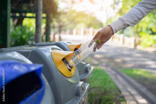 Woman throwing plastic bottles in the trash in the park.