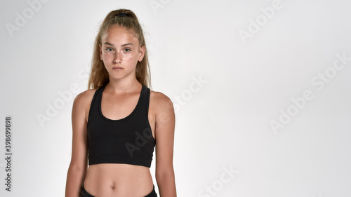 Portrait of cute sportive girl child in sportswear looking at camera, while posing isolated over white background
