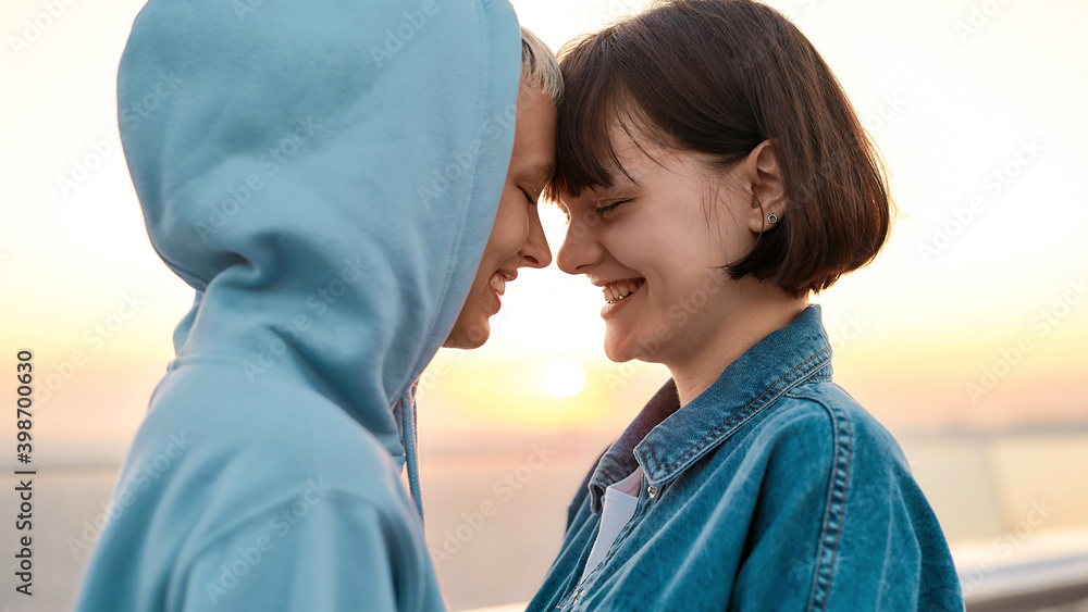 Close up of young loving lesbian couple smiling while going to kiss, Two women enjoying romantic moments together at sunrise Close up of young loving lesbian couple smiling while going to kiss, Two women enjoying romantic moments together at sunrise