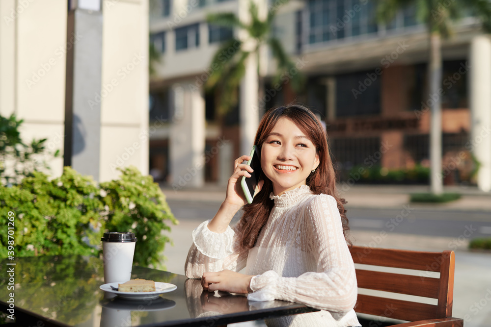 Young and beautiful Asian freelance business woman using a smart phone at the restaurant terrace in the urban city Young and beautiful Asian freelance business woman using a smart phone at the restaurant terrace in the urban city