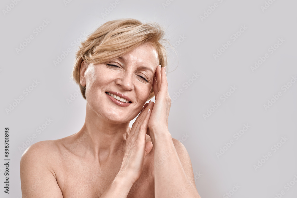 Close up portrait of beautiful middle aged woman in underwear showing sleep gesture while posing, standing isolated against grey background Close up portrait of beautiful middle aged woman in underwear showing sleep gesture while posing, standing isolated against grey background