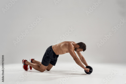 Young handsome muscular caucasian man with abs wheel