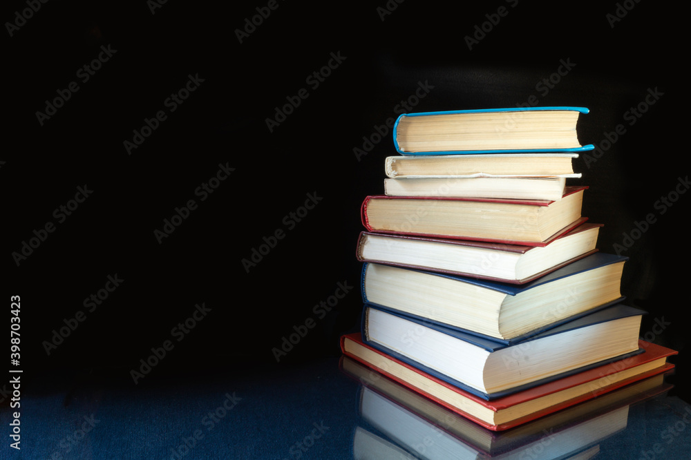 Fototapeta premium Stack of the books rests upon turn blue table with reflection