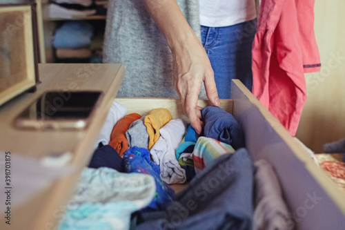 A woman is sorting through things in her home wardrobe with her hands. Folding clothes after washing. Household responsibilities, keeping the apartment clean and tidy
