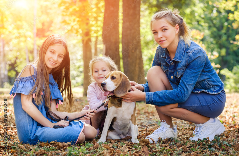 Cheerful children play with dog in autumn forest