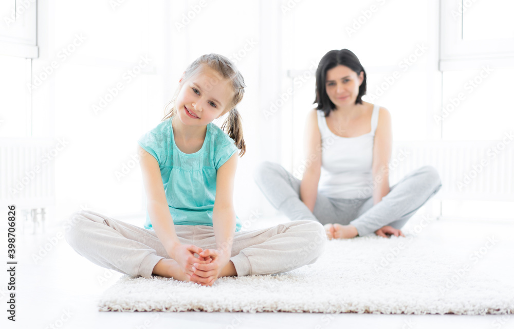 Cute little girl doing sports with mother in light room Cute little girl doing sports with mother in light room