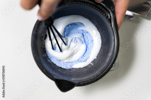 Obraz na plátne Hairdresser colorist kneads paint for hair dyeing