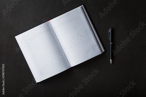 An open Notebook with a black pen on a black background. photo