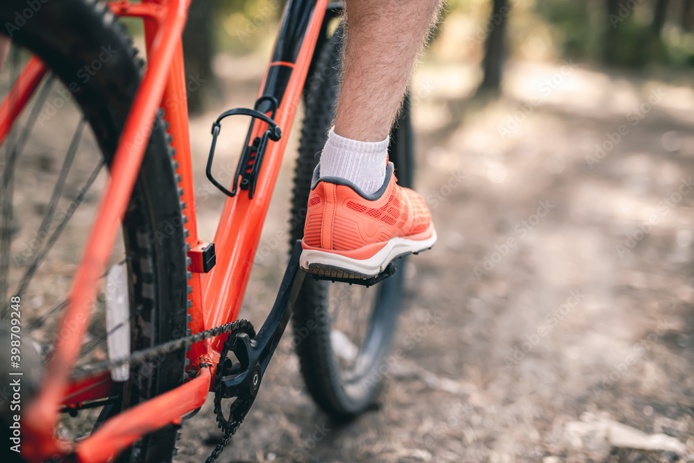 Leg in sneaker on bicycle pedal during riding outdoors Leg in sneaker on bicycle pedal during riding outdoors