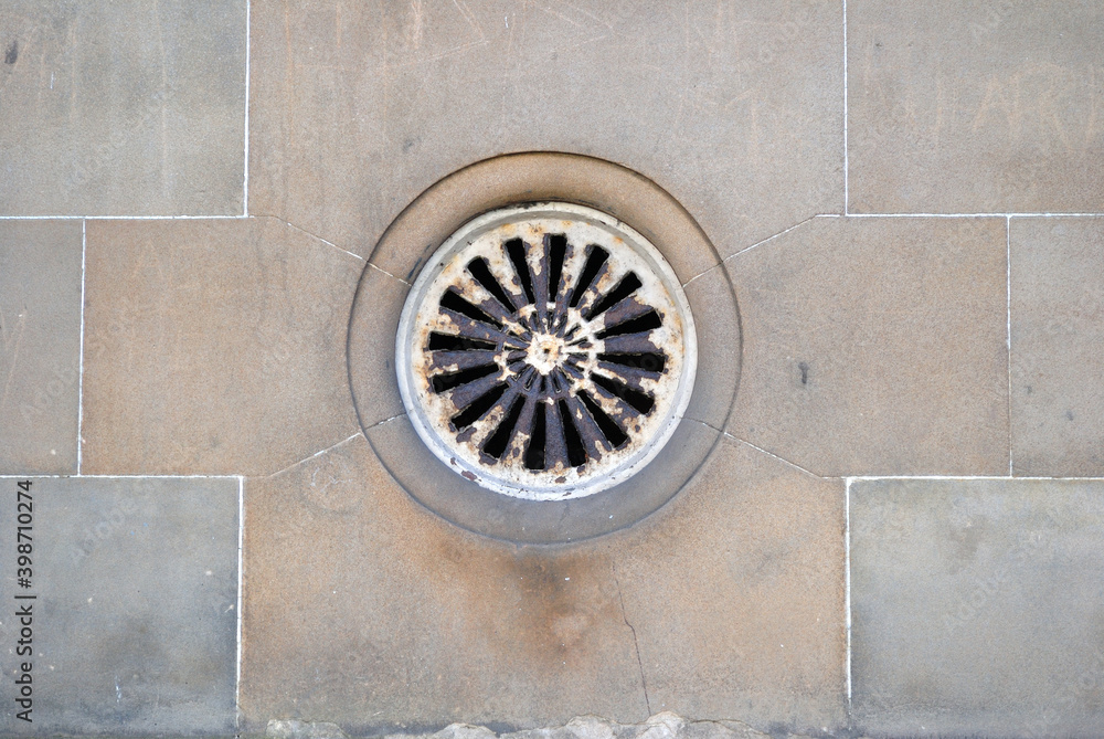 Close Up of Old Victorian Circular Iron Vent in Smooth Stone Wall