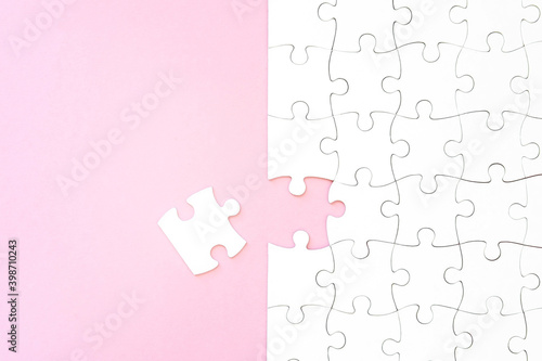 Last unconnected piece of white puzzle on pink background
