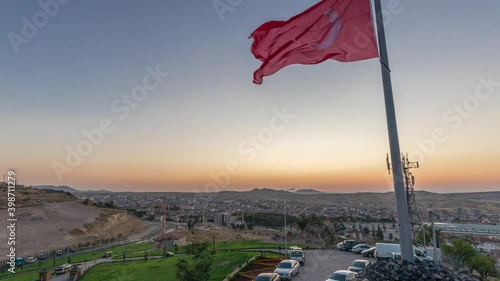 Sunset view from old castlethe in historical city town of Nevsehir aerial timelapse. Panoramic skyline with flag at evening photo