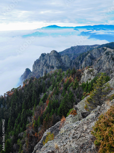 Vertical panorama of the view from Cozia peak covered by two layers of clouds. The blue mountain seen at the horizon is the Buila Massif. Cozia Massif is renown for its steep rocky abysses. Carpathia 